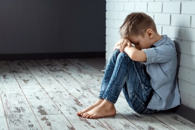 A Young Boy Sits Alone With A Sad Feeling At School Near The Wal